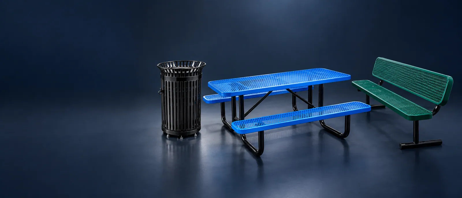 Illustration: a blue expanded metal picnic table, a green bench with backrest and a black slatted receptacle in a studio.